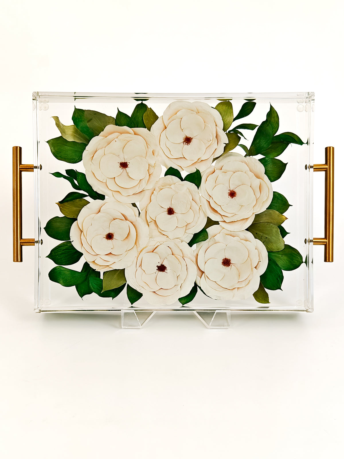 A clear acrylic serving tray with gold side handles, featuring a printed design of large white flowers and green leaves, displayed on a clean white background.