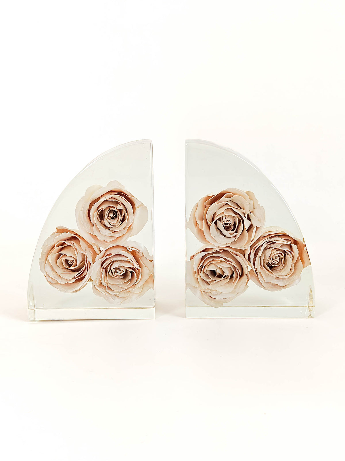 A pair of clear acrylic bookends shaped like semi-circles, decorated with three watercolor-style beige and pink roses on each piece, set against a plain white background.