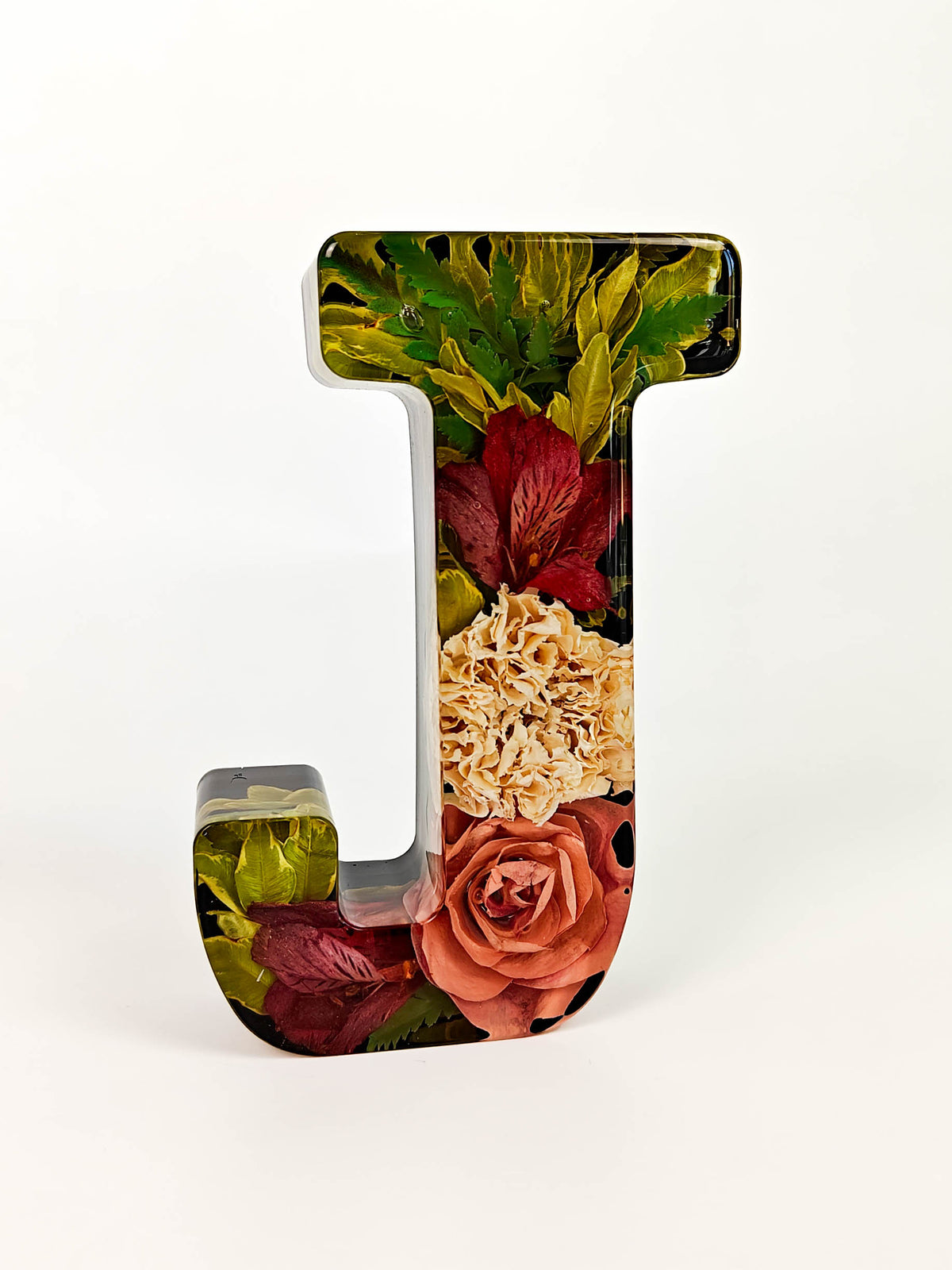 A decorative resin letter 'J' featuring an embedded floral design with red roses, cream hydrangeas, and green leaves on a white background.