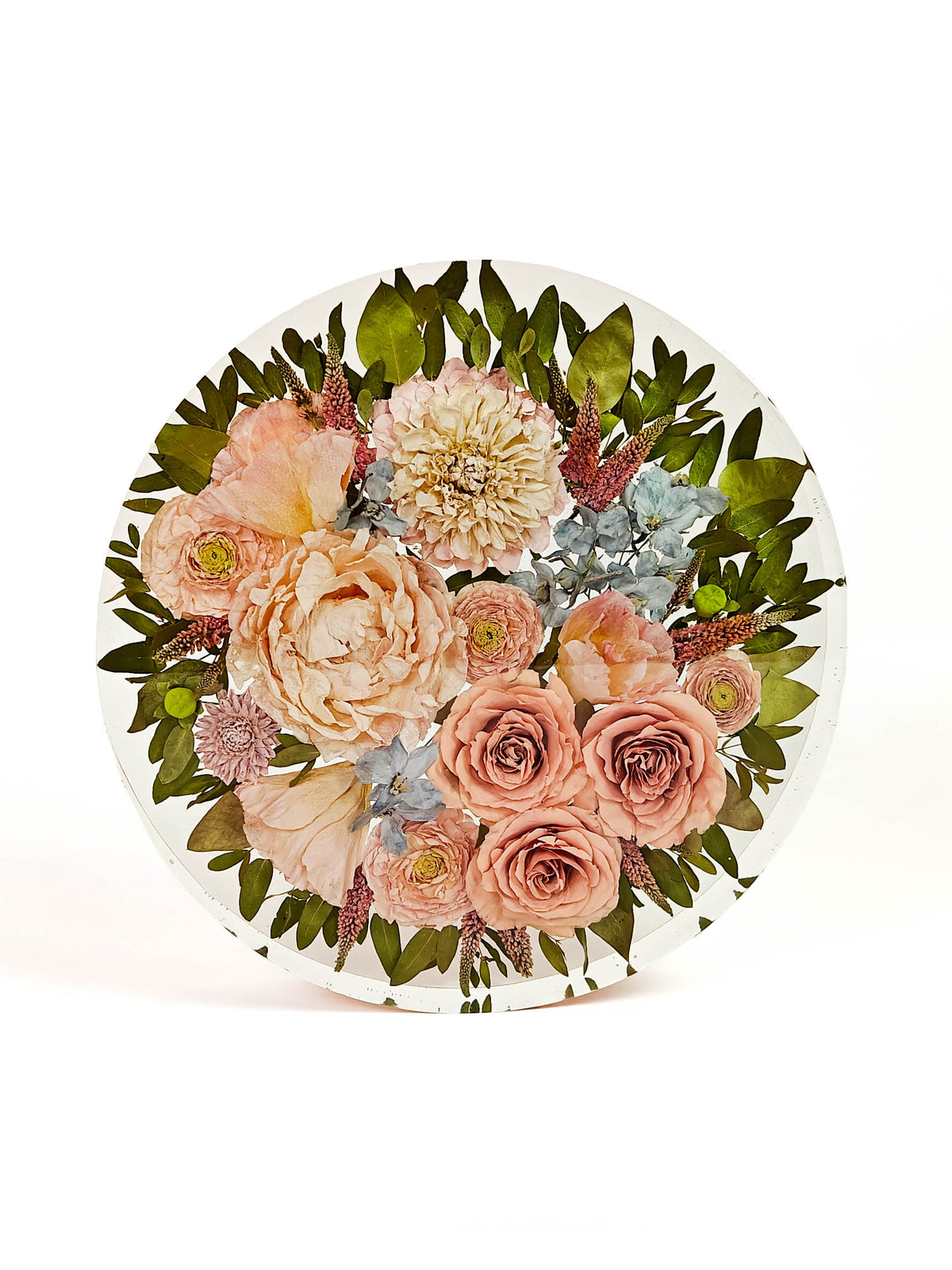 A round white plate featuring a detailed floral print of pressed flowers, including peach roses, cream peonies, green leaves, and light blue hydrangeas, shown on a clean white background.