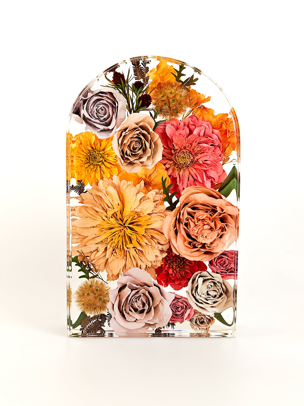 An arched clear resin plaque featuring a colorful arrangement of dried and pressed flowers, including orange, pink, peach, red, and beige blooms, set against a plain white background.
