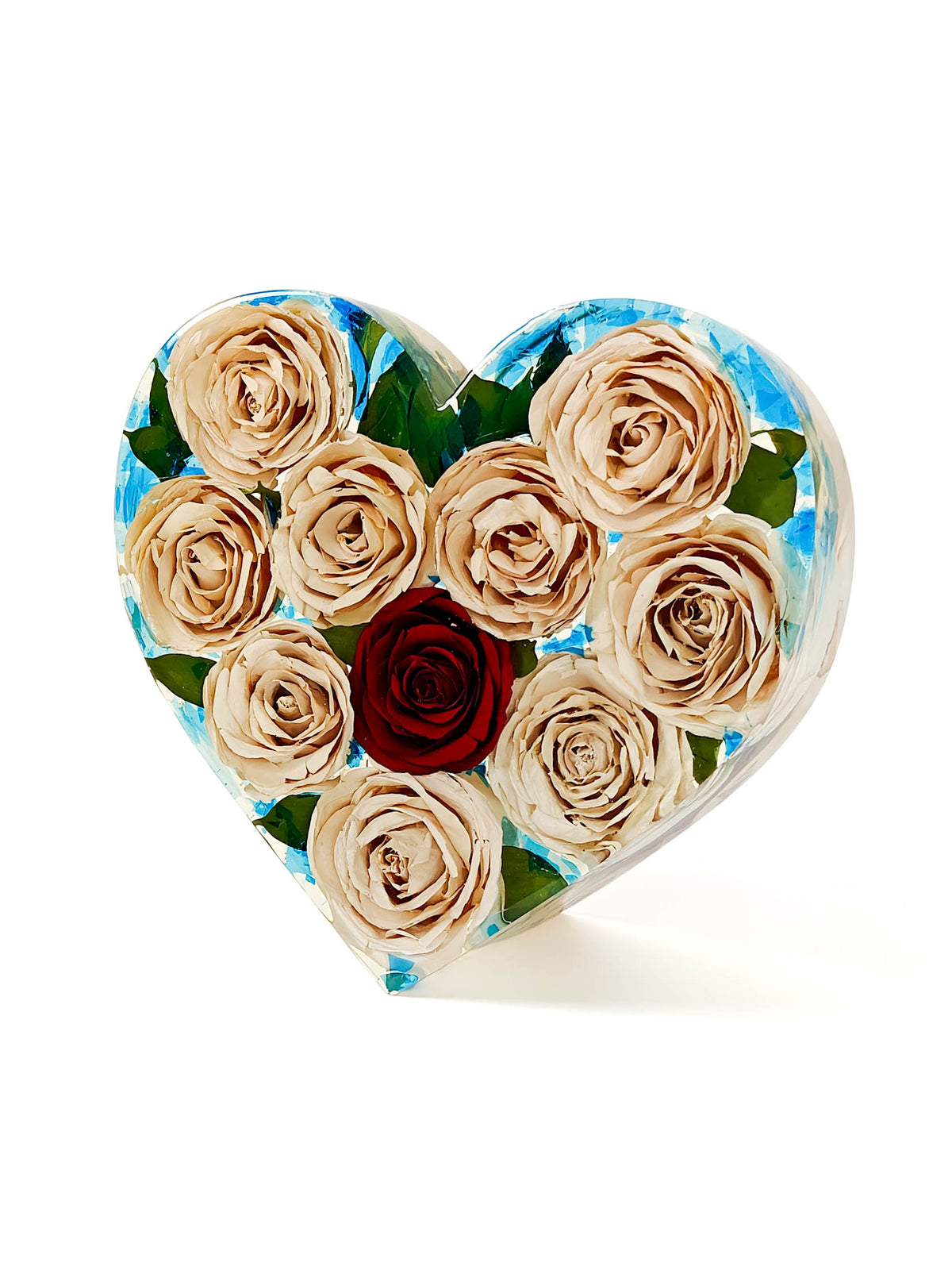 A heart-shaped decorative object featuring a floral design with beige roses, green leaves, and a single dark red rose in the center, set against a light blue marbled background.