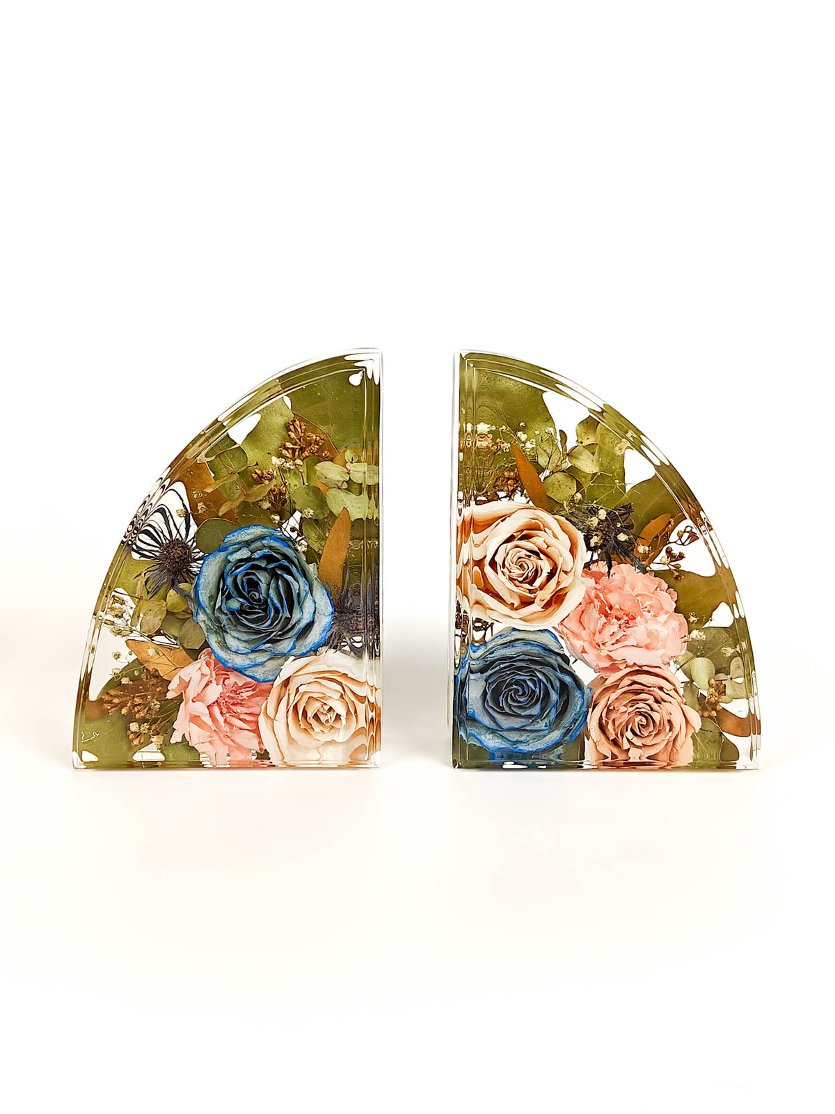 A pair of curved bookends featuring a detailed floral design with blue, pink, and peach roses, green foliage, and small butterflies enclosed in clear resin on a white background.