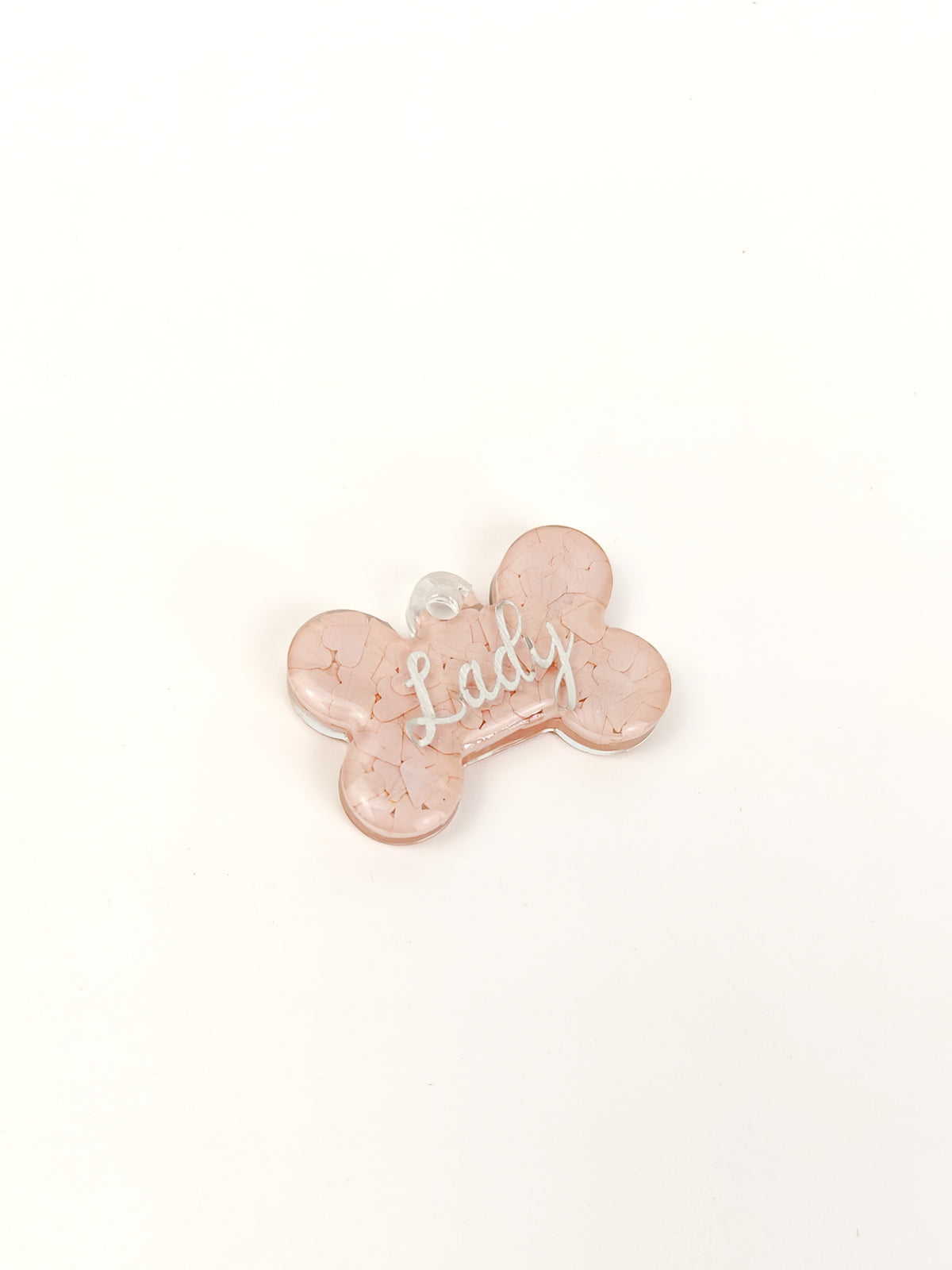 A small bone-shaped pendant or charm in a pale pink marbled resin with the word 'Lady' written in silver script across the center, shown on a plain white background.